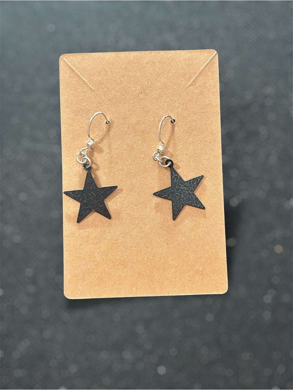 Kids black five point star dangle earrings featuring textured star charms